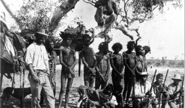 Chained aboriginal prisoners posed with a policeman and Aboriginal trackers, circa 1890